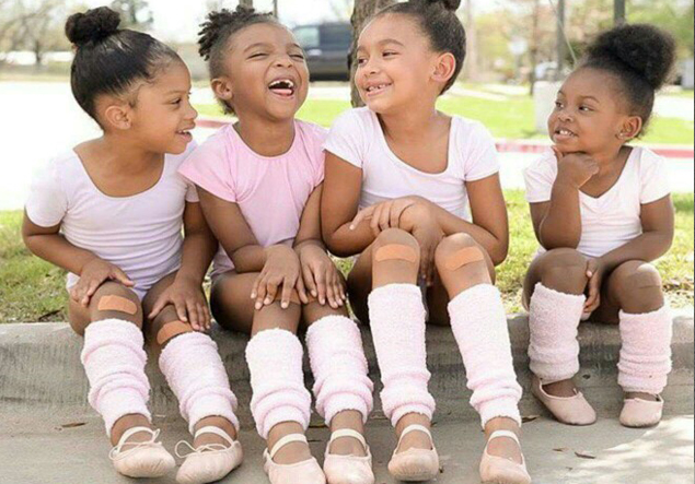3 little black girls sitting and laughing on the curb